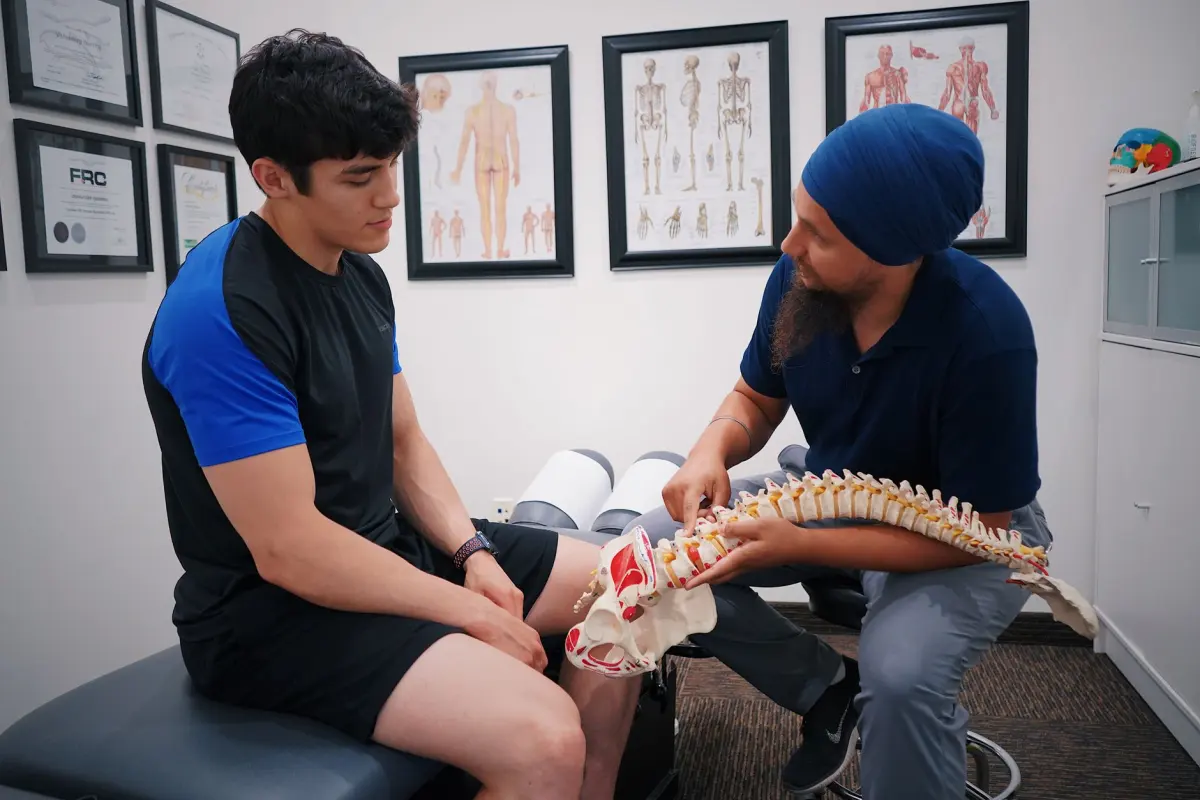 A doctor explains spinal issues to a patient using a spine model during a medical consultation, chiropractor mandurah