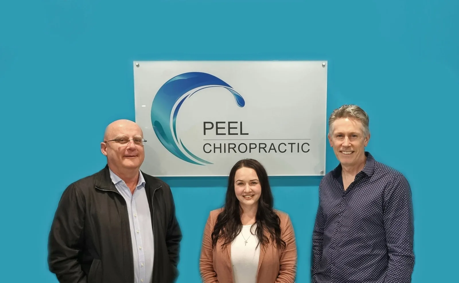 Dr Sean Eastwood, Dr Jessyca Rowe and Dr Brett Watson standing in front of the Peel Chiropractic sign at the clinic