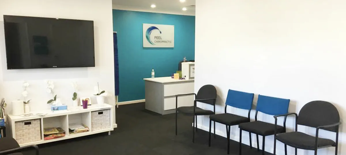 The Peel Chiropractic waiting room and reception desk, with the clinic's logo on the teal wall