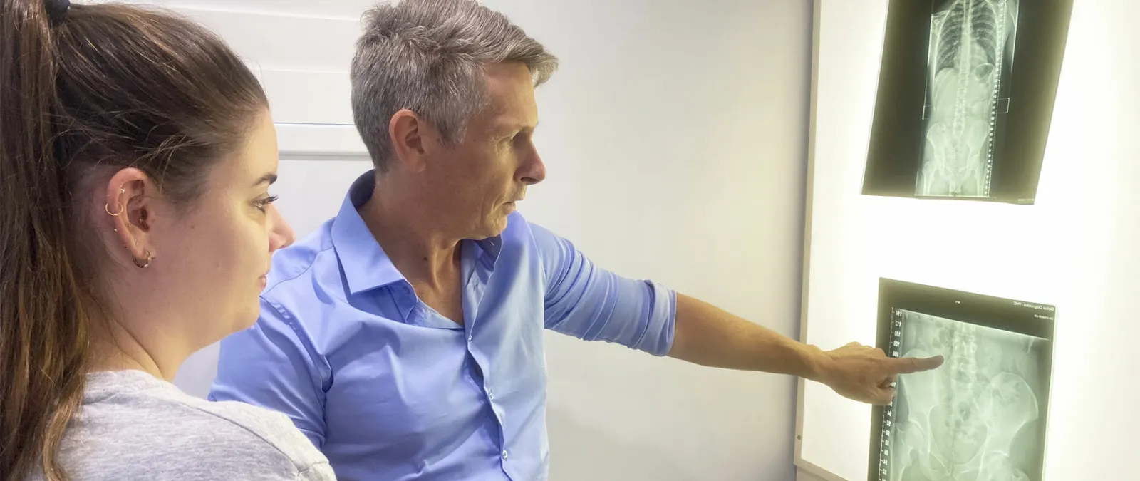 Dr Brett Watson points out the spine on a patient's x-rays at the lightbox